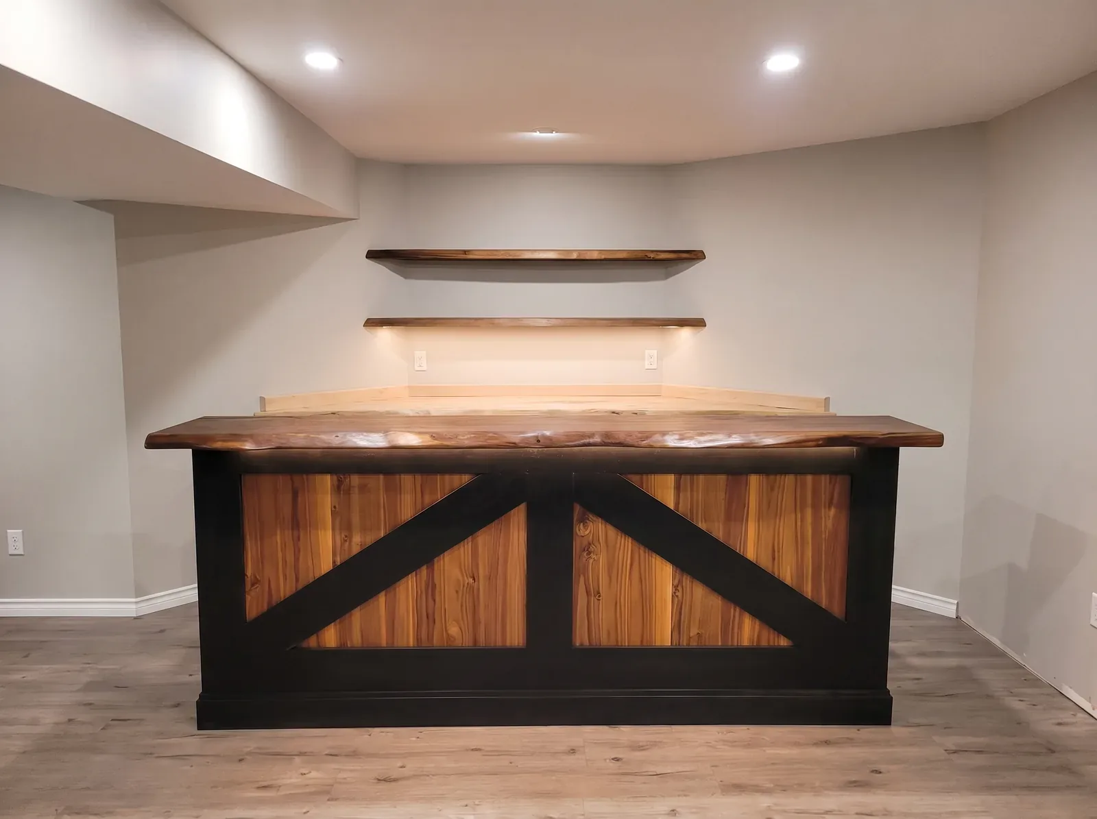 Basement bar with a live-edge walnut top, barn-frame base and floating live-edge shelves