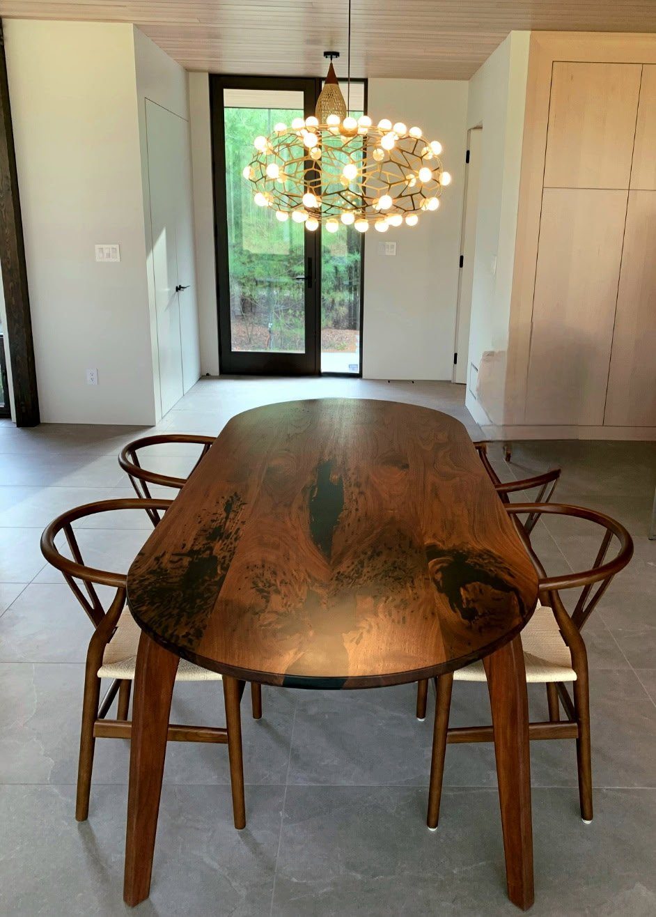 Oval black walnut dining table with epoxy detail and wishbone chairs